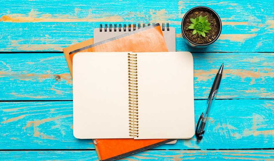 A high-angle view of a blank notebook and pen on a wooden table