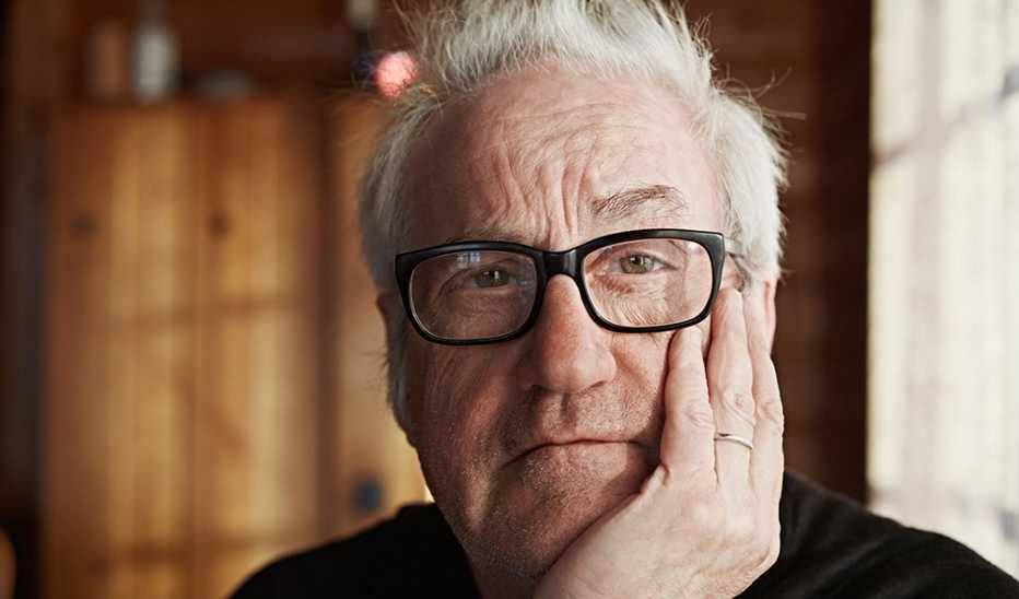 A man staring straight ahead with his hand on his head
