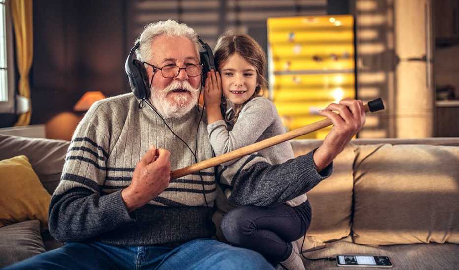 A man and girl on a couch listening to music in headphones