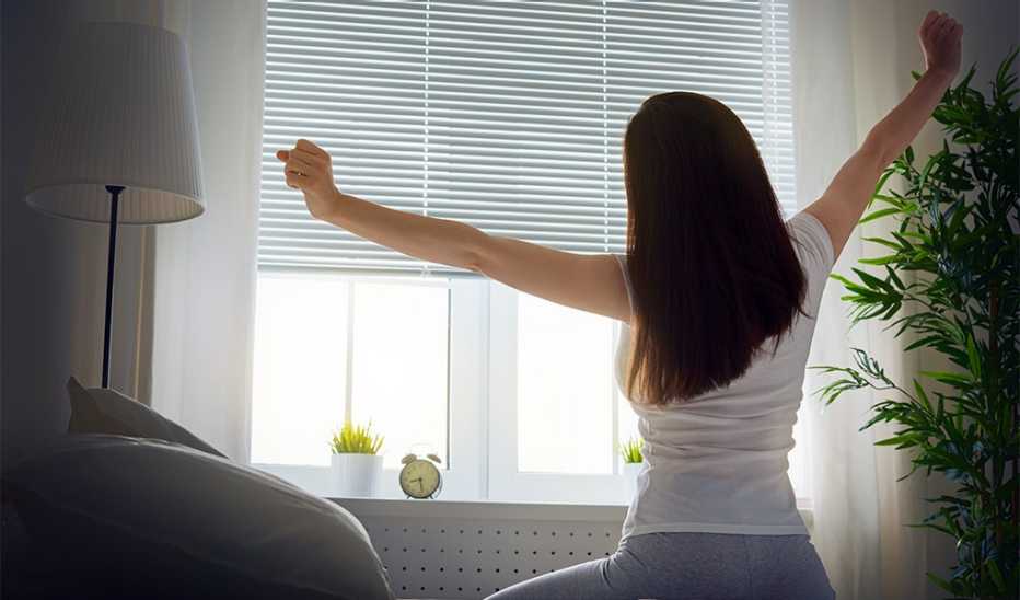 A woman stretching as she gets out of bed