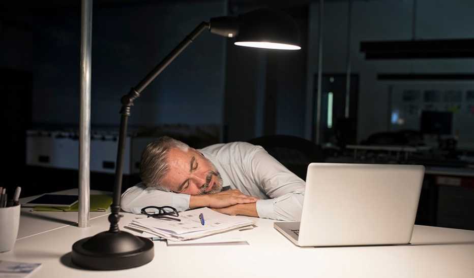 A man napping at a desk at night