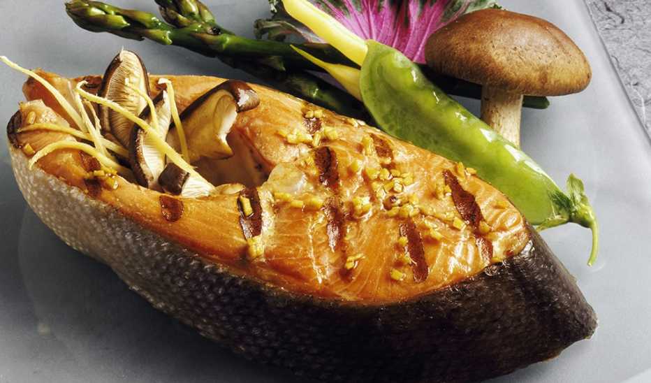 A close-up view of grilled salmon steak with mushrooms, asparagus, snow peas and beans