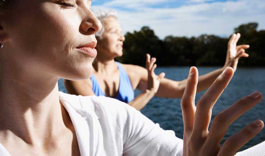 A close-up view of two women doing tai chi by a lake