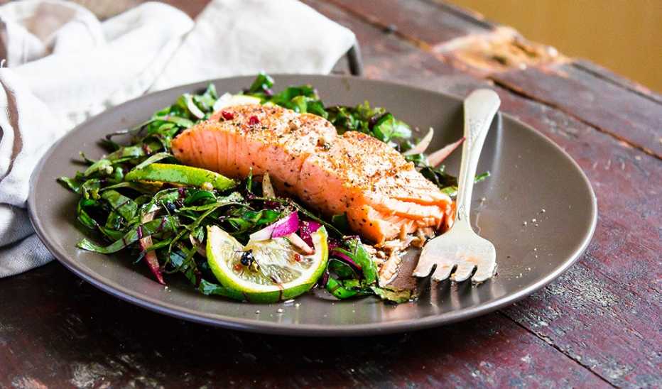 An up-close view of salmon fillet steak roasted with spices served with fresh salad