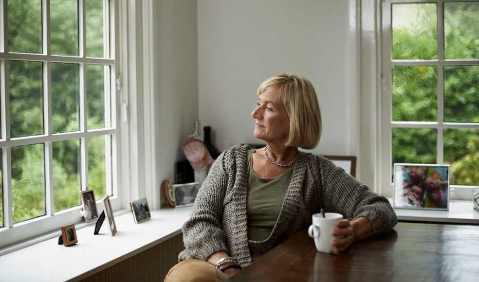 A woman having coffee at a table and looking out a window