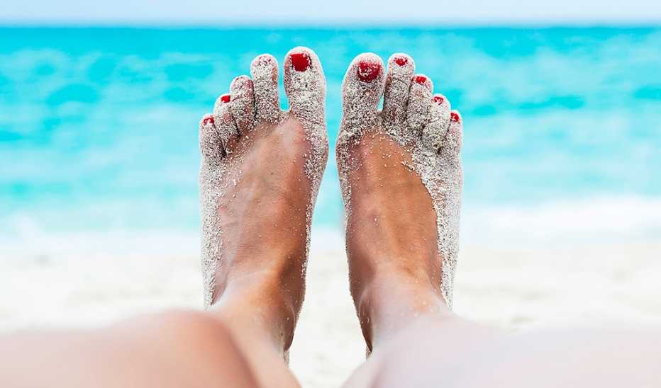 Two sandy feet of a person lying on the beach