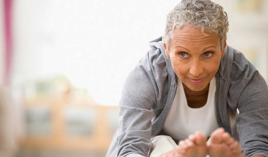 A woman leaning forward to stretch her legs on a yoga mat