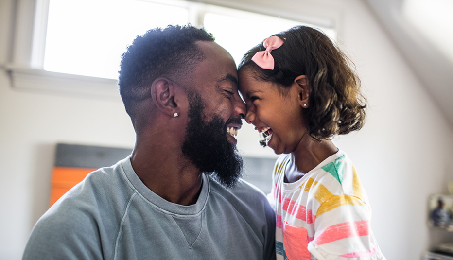 A man and a young girl laughing with their heads touching