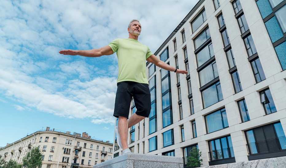 A man balancing on one leg on concrete outside of a building 