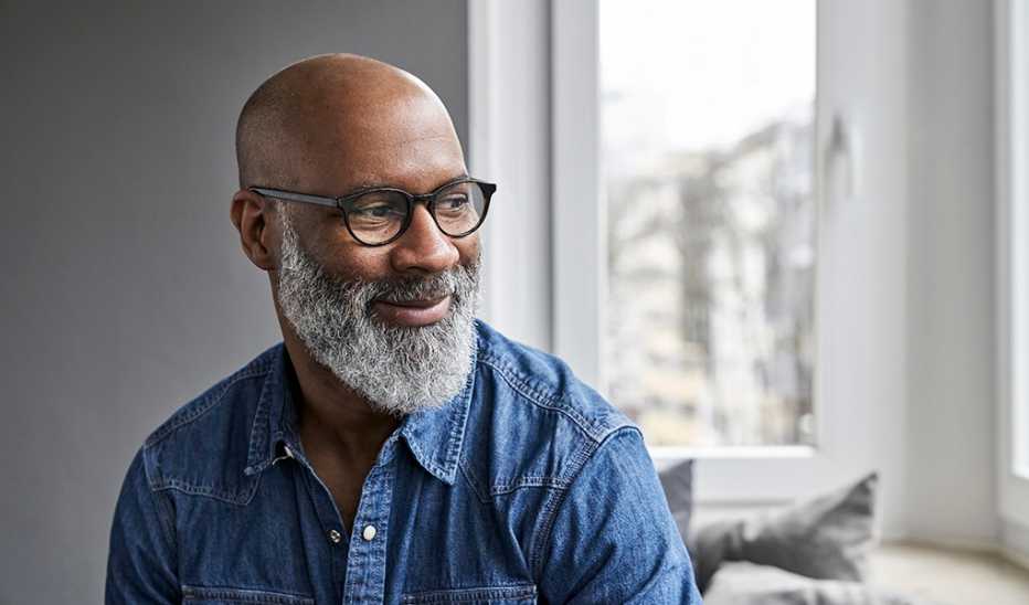 An up-close portrait shot of a man smiling inside a home