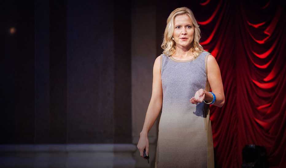 A woman, Emily Balcetis, speaking on stage at a TED event