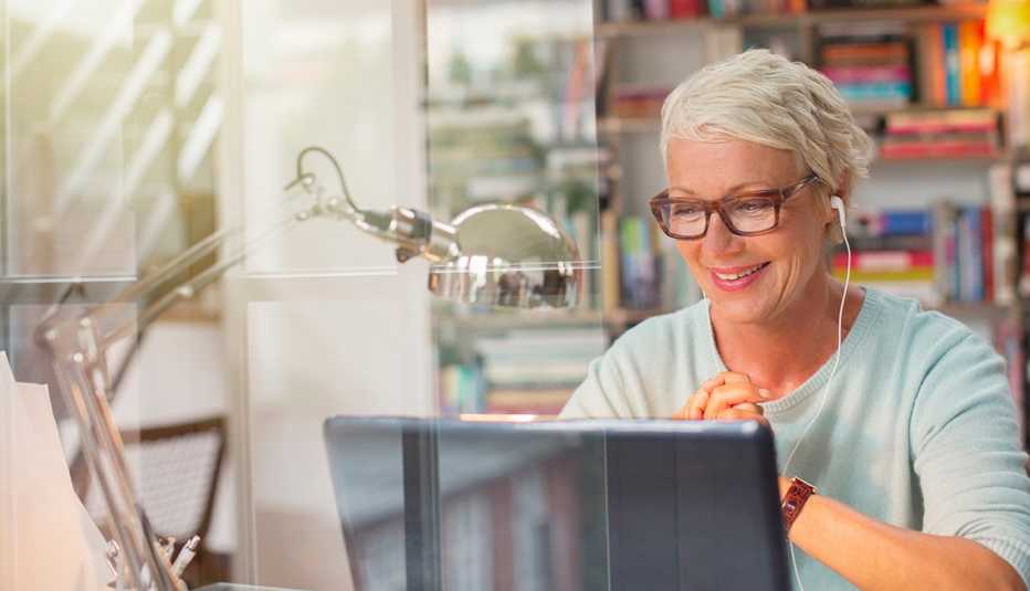 A woman wearing earphones and looking at a computer with earphones