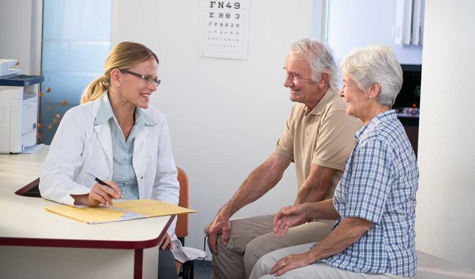 A man and woman speaking with a female doctor at a desk