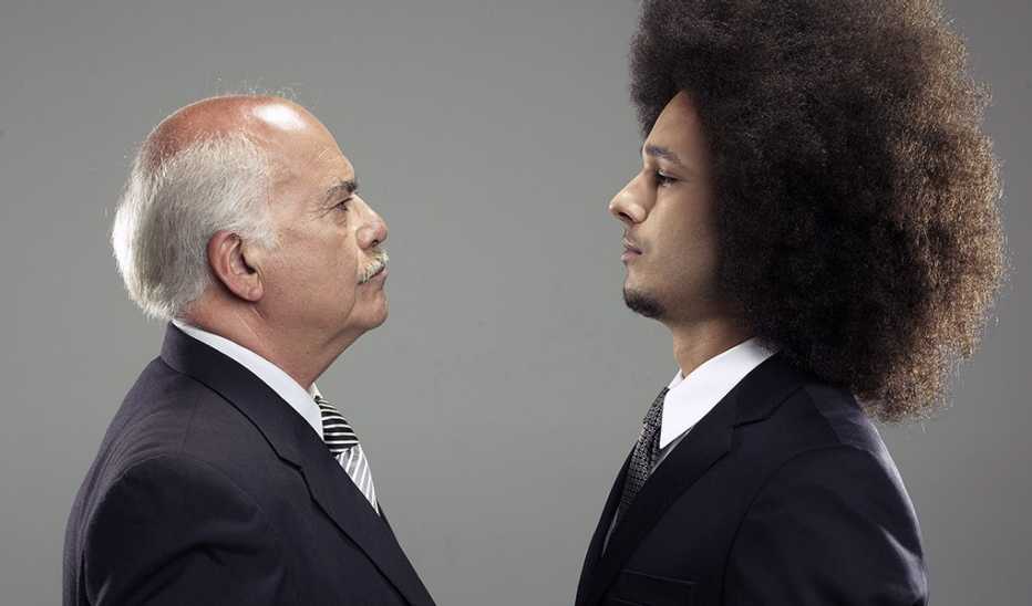 An older man and younger man in business attire staring at each other