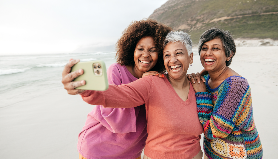 Three women taking a selfie on the beach and laughing together