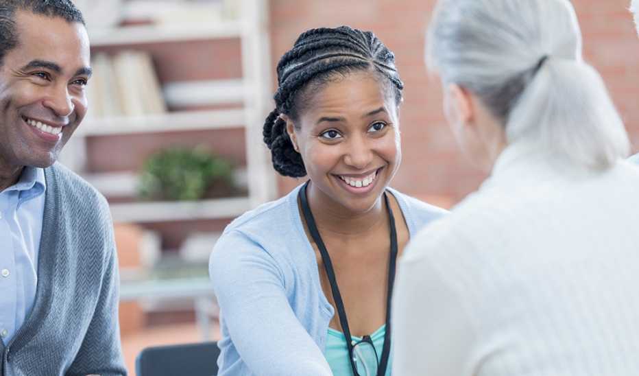 A smiling female psychologist comforts a senior patient during a group therapy session