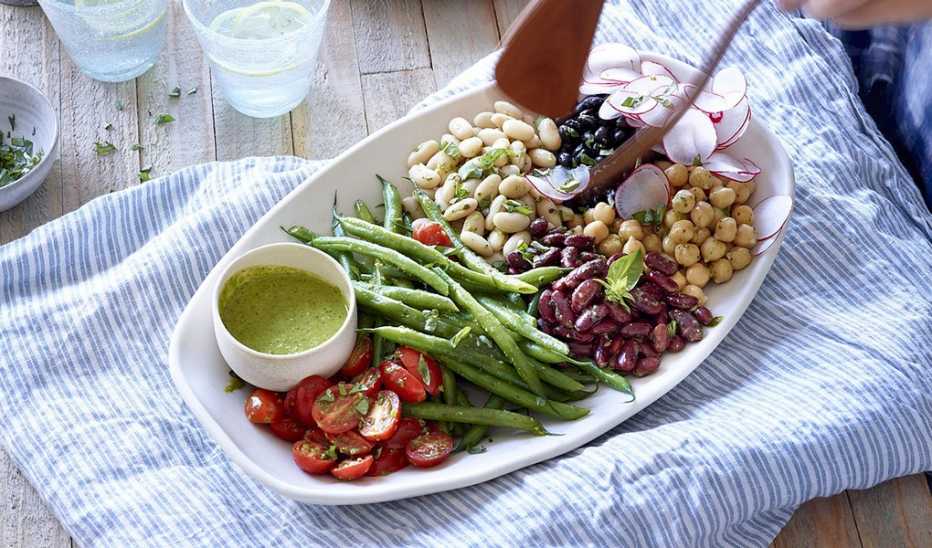 A close-up view of composed bean salad with basil vinaigrette on a plate
