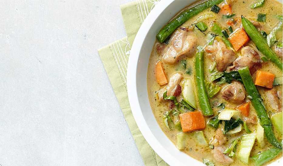 A close-up view of green chicken curry in a bowl
