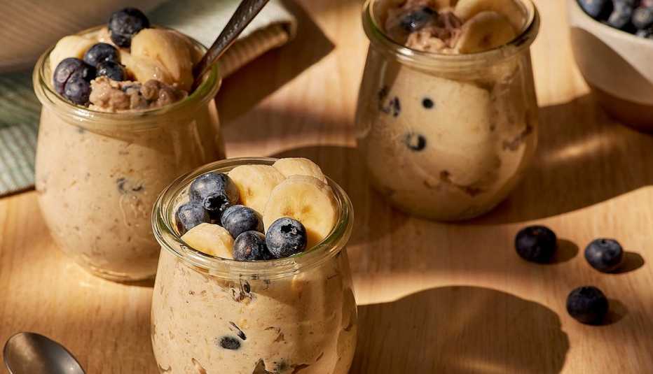 A close-up view of high-protein peanut butter, banana and blueberry overnight oats in glasses