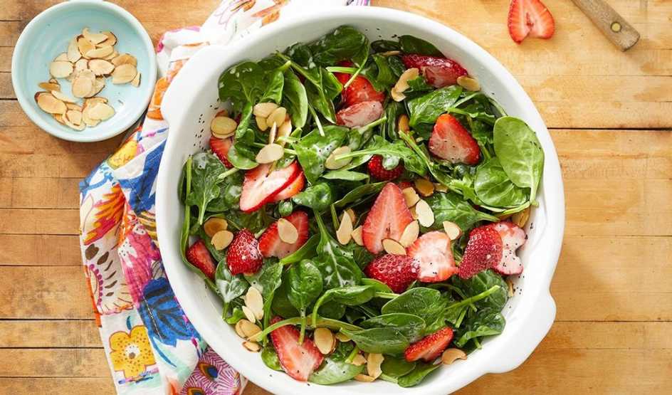 A close-up view of spinach and strawberry meal-prep salad in a bowl