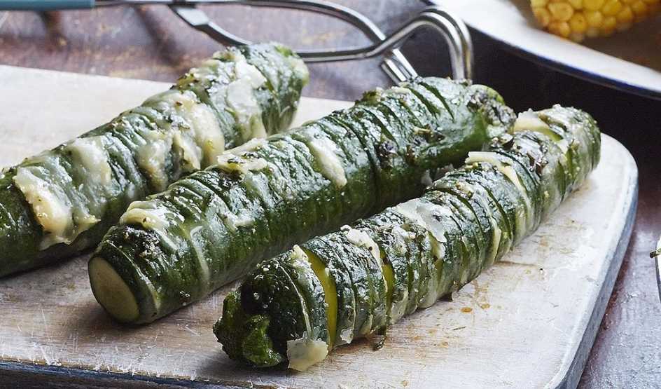 A close-up view of garlic-parmesan hasselback zucchini on a board A close-up view of garlic-parmesan hasselback zucchini on a board
