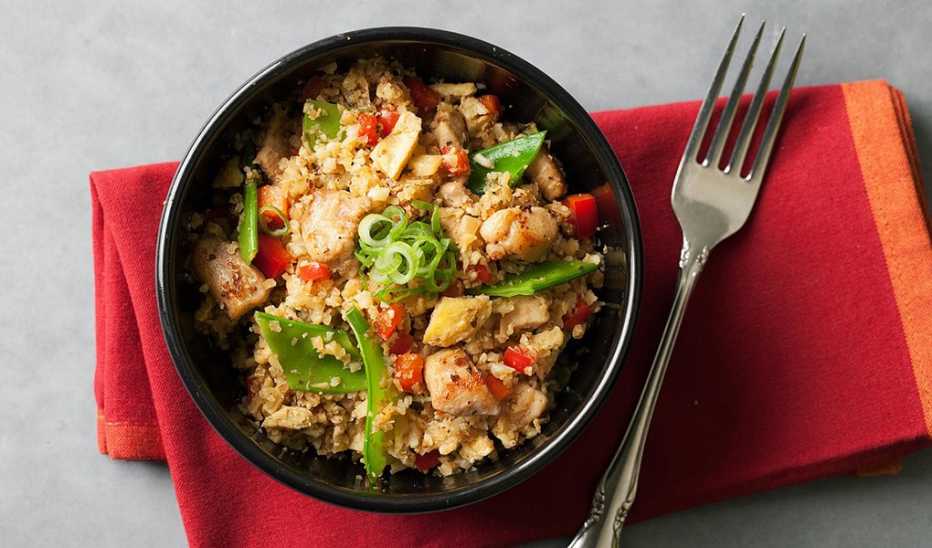 A close-up view of a cauliflower chicken fried rice in a bowl