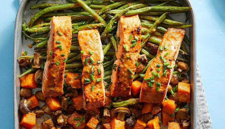 Ginger-tahini oven-baked salmon and vegetables A close-up view of ginger-tahini oven-baked salmon and vegetables on a sheet pan