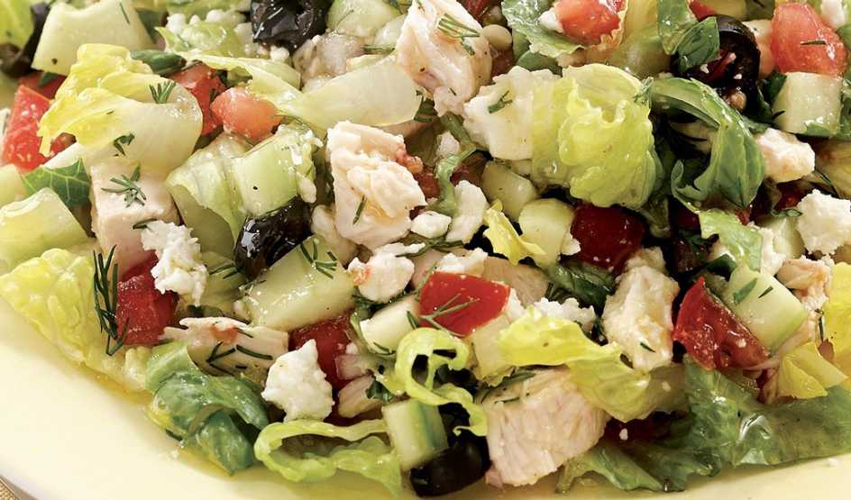 A close-up view of a chopped Greek salad with chicken on a plate