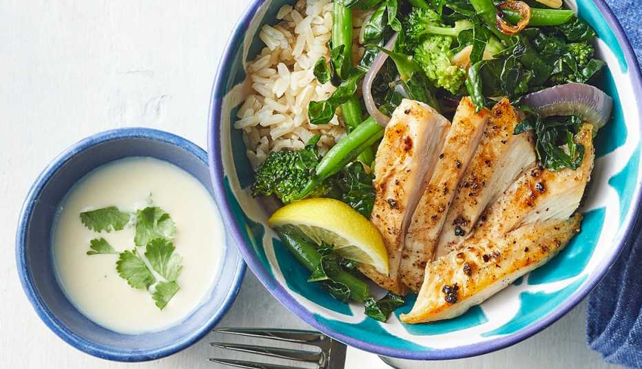 Green veggie bowl with chicken and lemon-tahini dressing A close-up view of a green veggie bowl with chicken and lemon-tahini dressing in a bowl