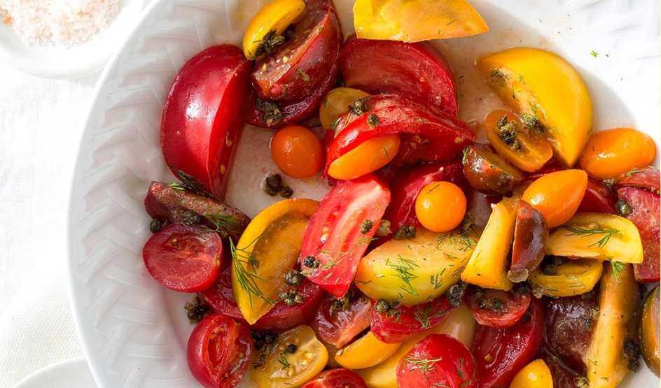 A close-up view of heirloom tomato salad with fried capers on a plate