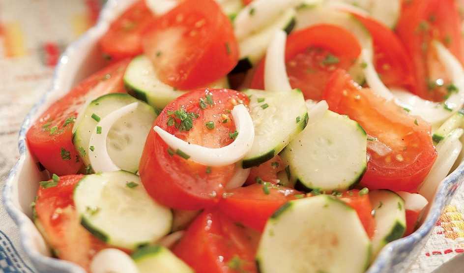 A close-up view of summer tomato, onion and cucumber salad in a bowl