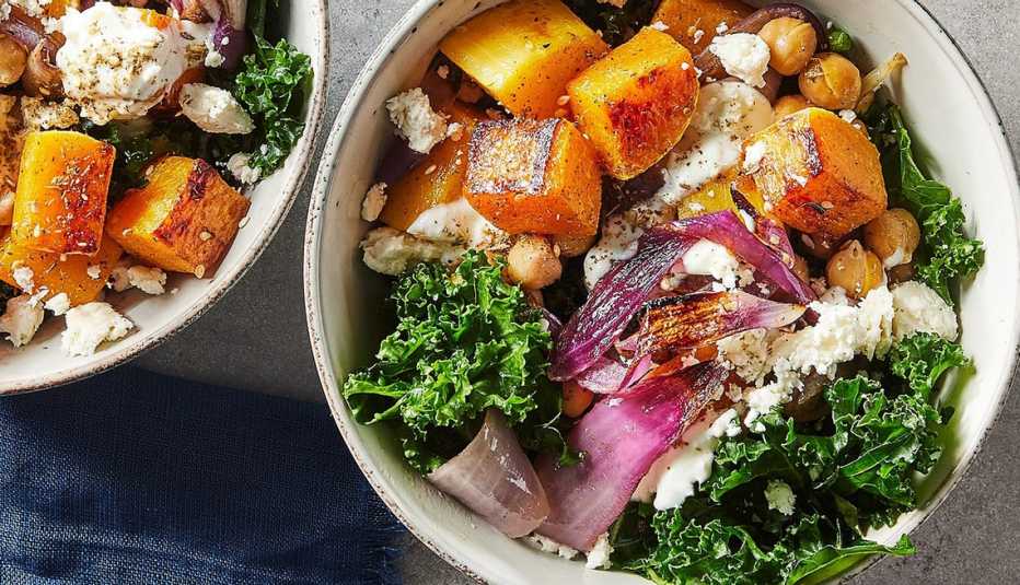 Massaged kale salad with roasted squash and chickpeas A close-up view of massaged kale salad with roasted squash and chickpeas in bowls