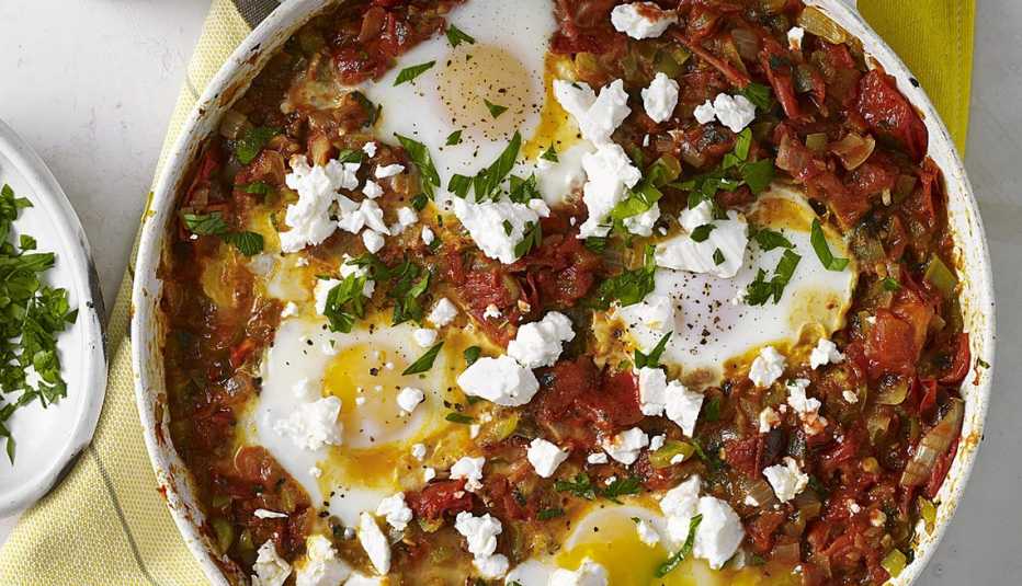A close-up view of shakshuka with roasted tomatoes (eggs poached in roasted tomato sauce) in a bowl