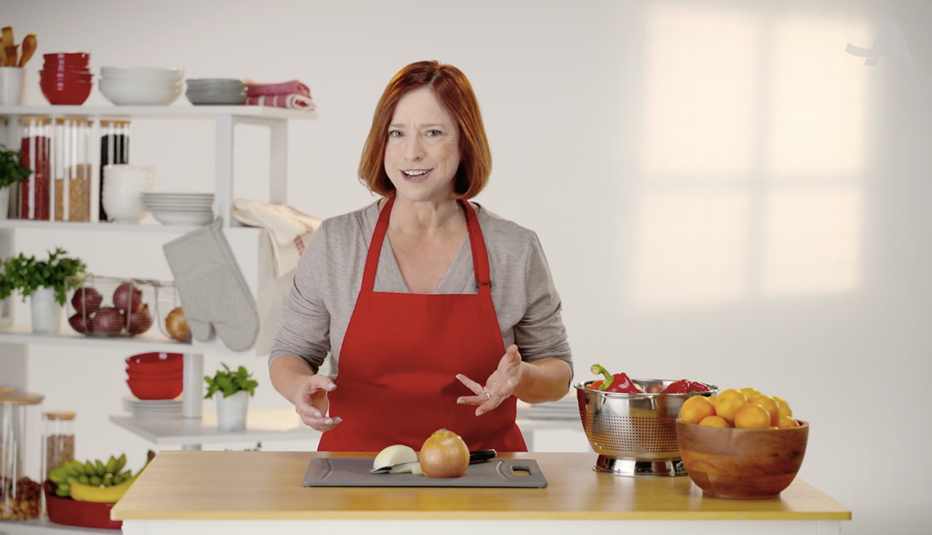 A woman standing in front of a cutting board with vegetables on it