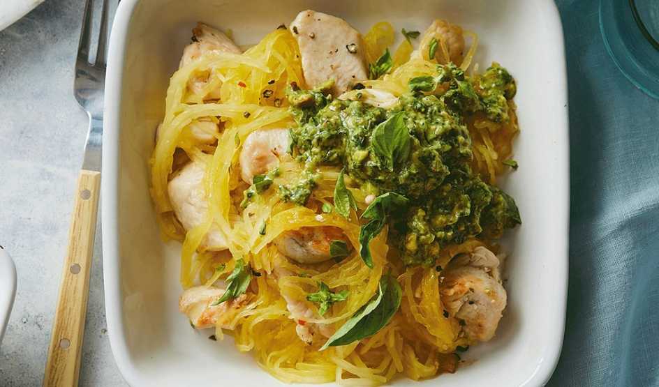 A close-up view of spaghetti squash and chicken with avocado pesto on a plate