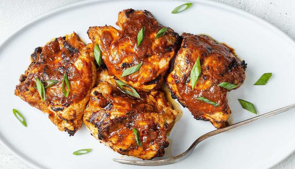 A close-up view of grilled harissa chicken thighs on a plate