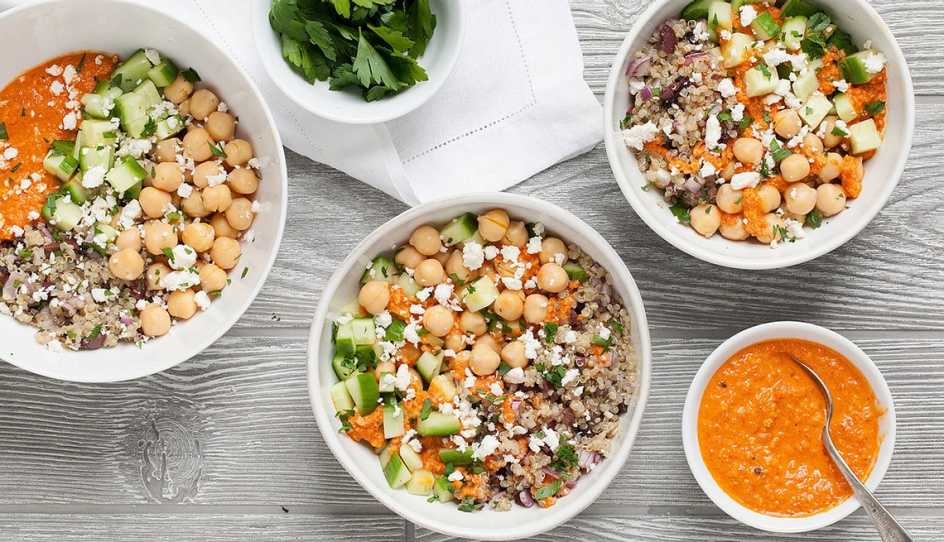 A close-up view of chickpea and quinoa bowls with roasted red pepper sauce