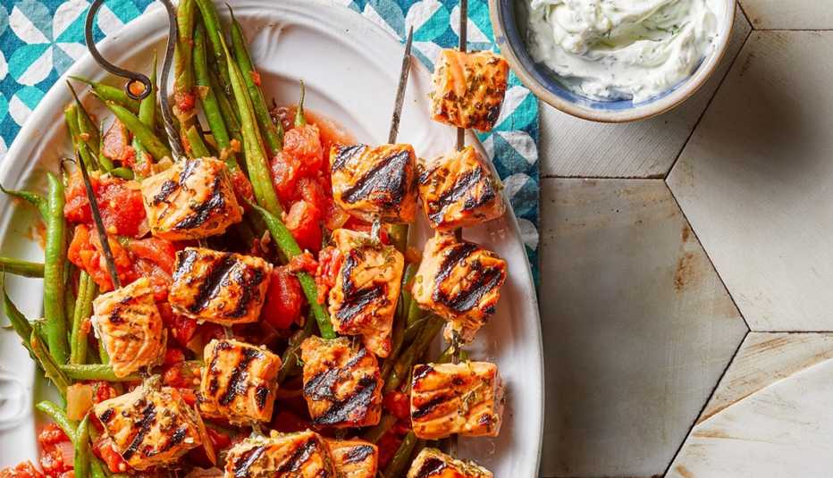 Salmon souvlaki with tzatziki and green beans A close-up view of salmon souvlaki with tzatziki and green beans on a plate