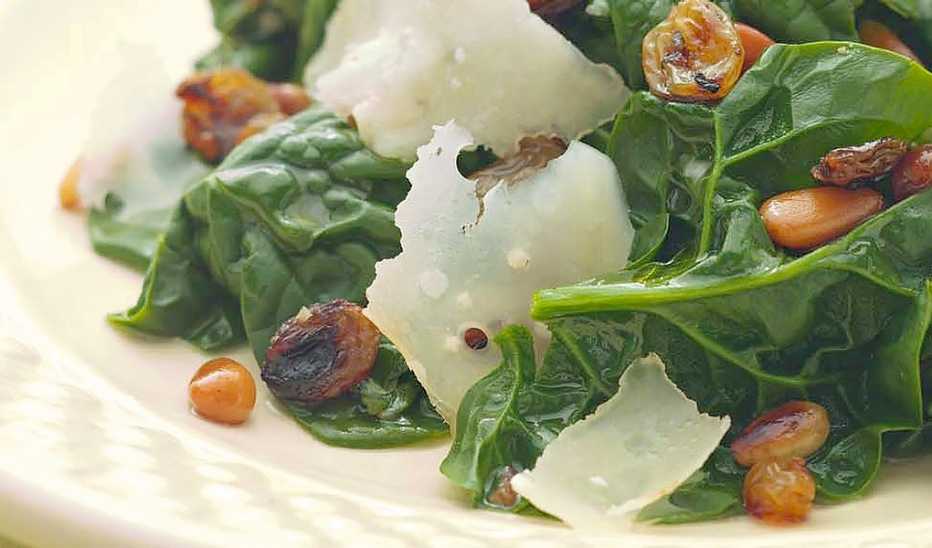 Sautéed spinach with pine nuts and raisins A close-up view of sautéed spinach with pine nuts and raisins on a plate