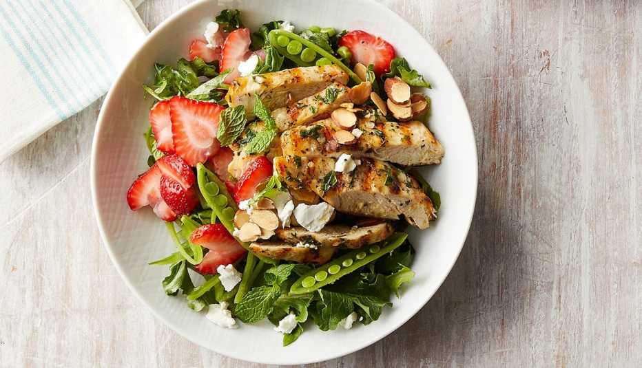 Strawberry chicken salad with mint and goat cheese A close-up view of a strawberry chicken salad with mint and goat cheese in a bowl