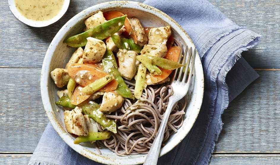 A close-up view of carrot, snow pea and chicken stir-fry in a bowl