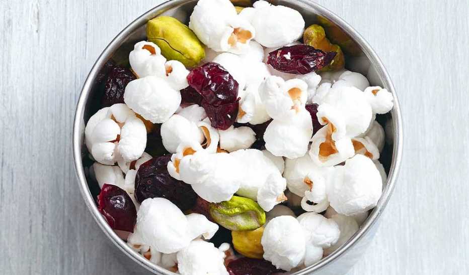 A close-up view of fruit and nut popcorn trail mix in a bowl