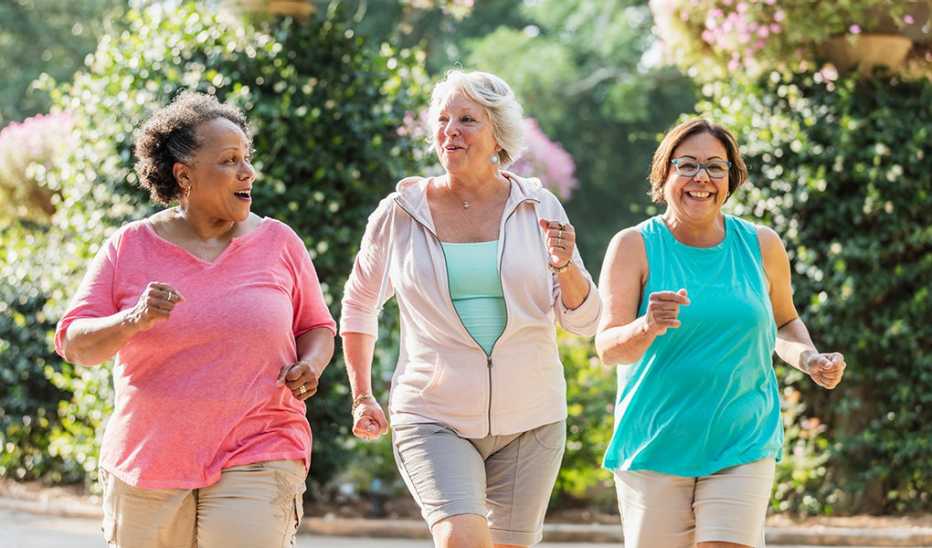 Three women smiling and power walking together outside