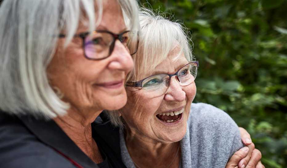 Two women smiling and hugging each other in a garden