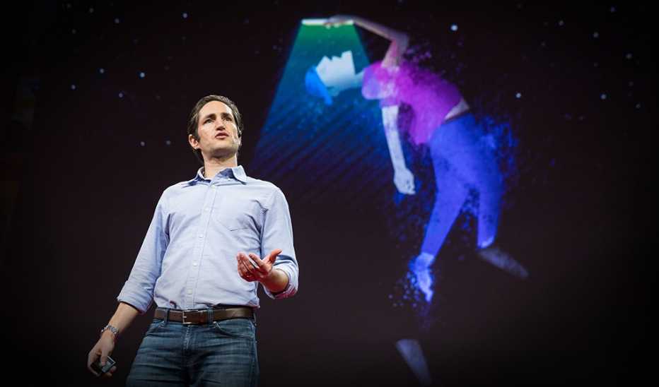 A man, Adam Alter. speaking on stage at a TED event