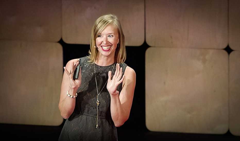 A woman, Mandy Len Catron, speaking on stage at a TED event
