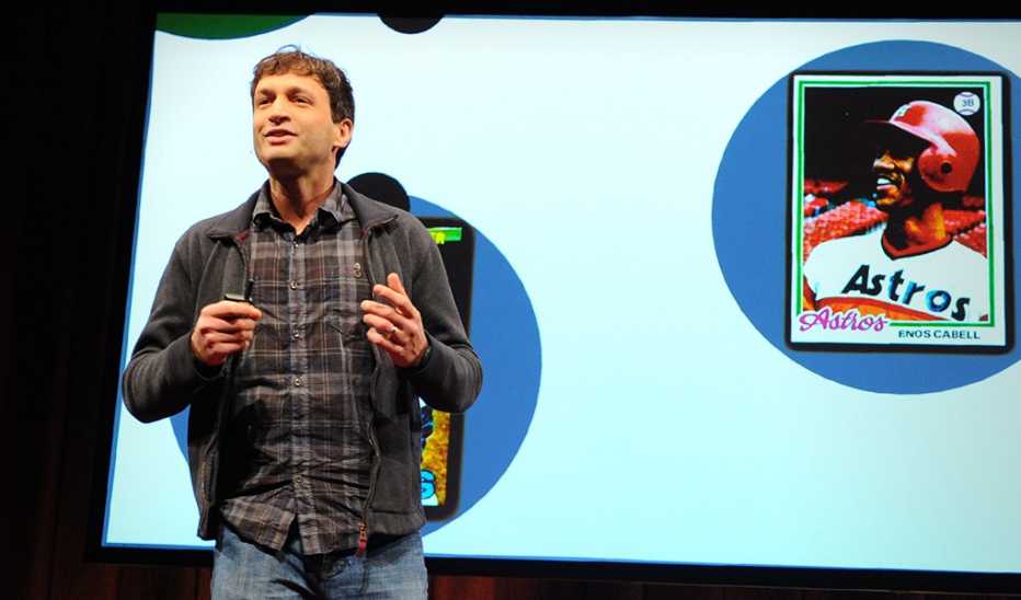 A man, Ron Gutman, speaking on stage at a TED event