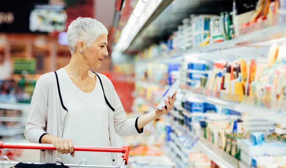 A woman grocery shopping with a cart at a store