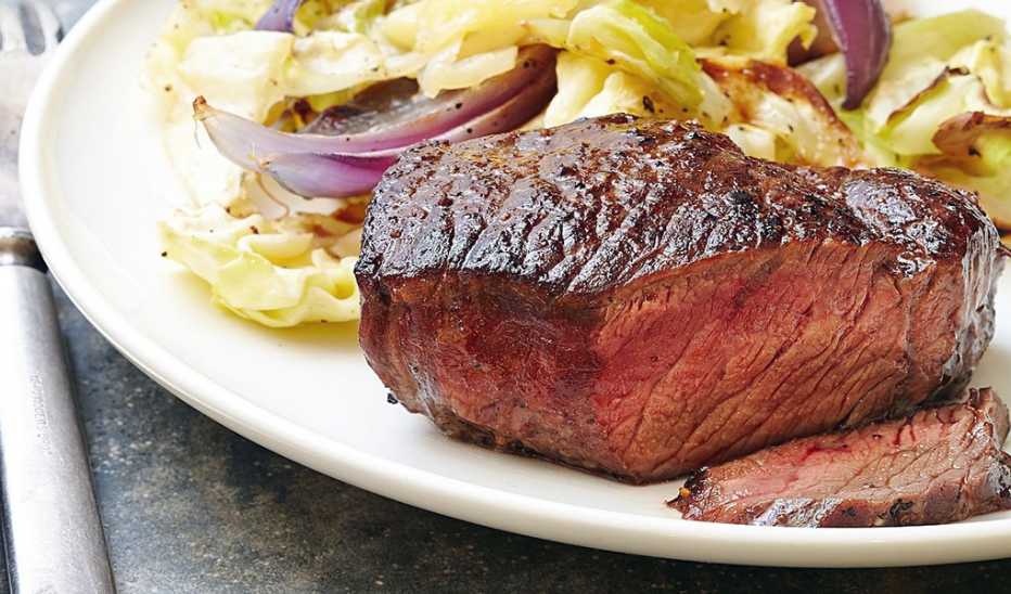 A close-up view of steak with cheddar roasted cabbage on a plate