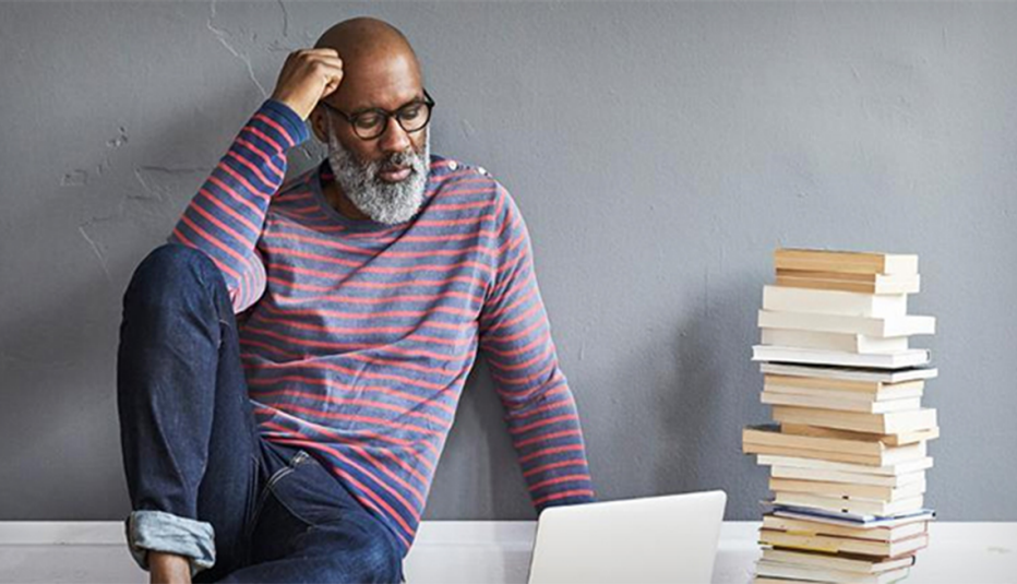 A man sitting on the floor and looking at a laptop